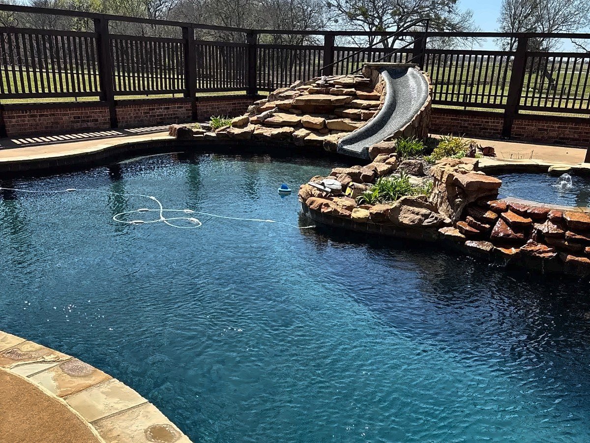 Freeform pool with a boulder waterfall, rock slide and spa